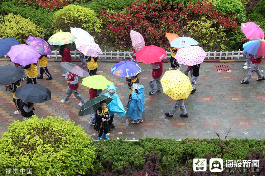 威海迎降雨天气 孩子打伞出行如雨中花朵