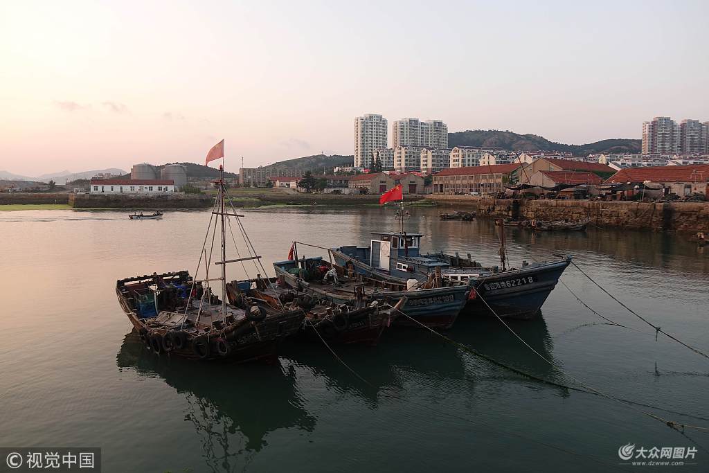 7月21日,黄昏时分的青岛西海岸大湾渔港,夕阳西沉,海面微澜,渔船静泊