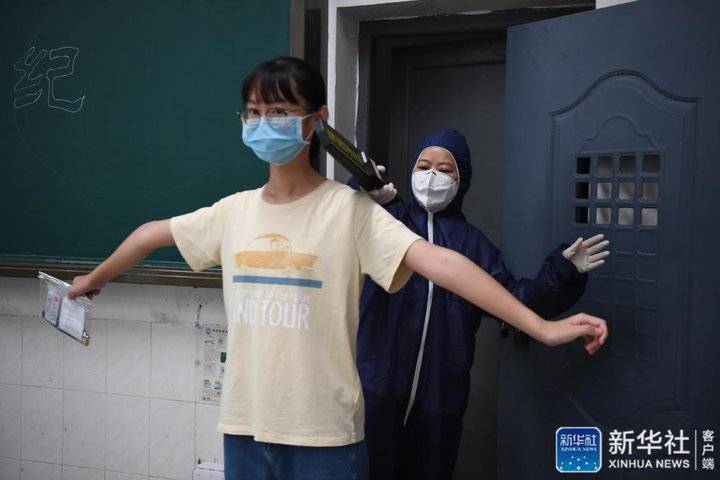 ↑7月3日，工作人员（右）模拟为发热考生进行安检。新华社记者 薛宇舸 摄