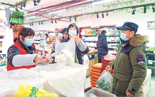 冯留海（右一）和妻子在家门口的超市买菜和馒头。（□记者王兆锋报道）