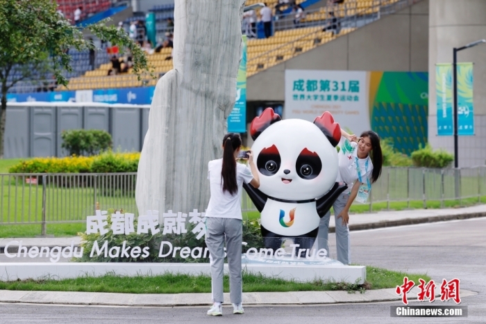 志愿者在比赛场馆外与吉祥物景观合影。中新社记者 韩海丹 摄